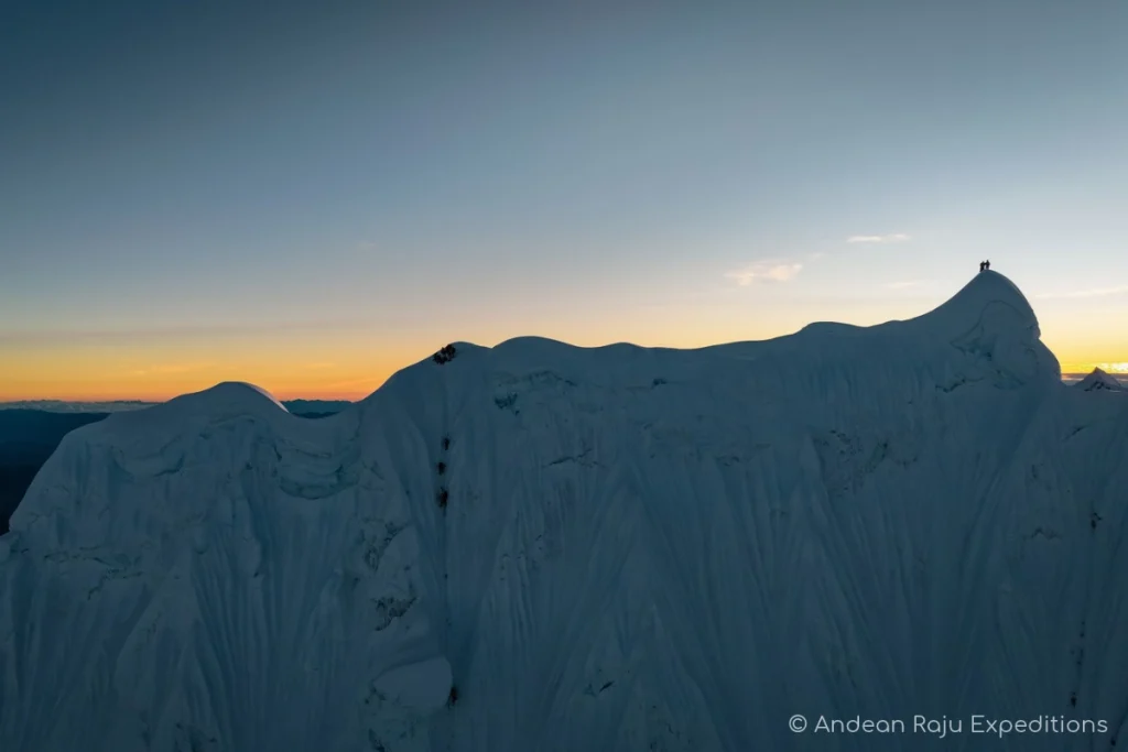 Rope team climbing the Ferrari route runnel on Alpamayo at dawn
